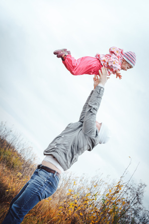 Father and his daughter child girl have fun in the field in an autumn dayの写真素材