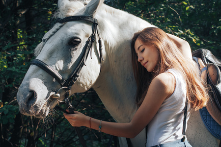 Girl teenager and white horse in a park in a summer dayの写真素材
