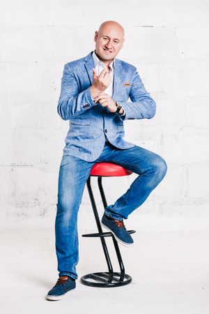 Bald businessman in a blue suit around the white brick wallの写真素材