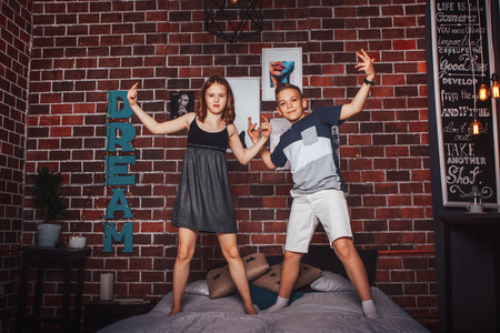 Nice children boy and girl have fun together on the bedの写真素材