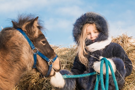 Small girl and small horse in a winter dayの写真素材