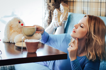 Blond woman in blue dress have rest in cafeの写真素材