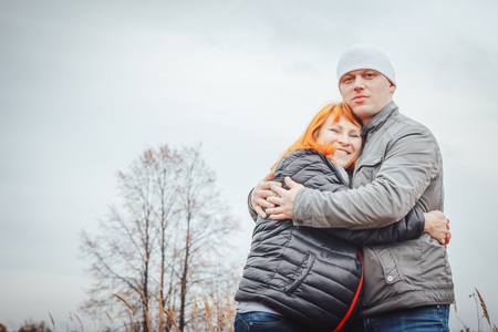 Couple consisting man in white hat and woman with red hair outdoors in an autumn day