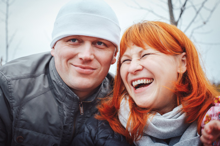 Couple consisting man in white hat and woman with red hair outdoors in an autumn dayの写真素材