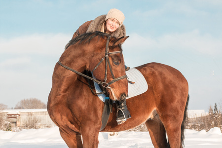 Woman in brown dress and brown horse in a winter dayの写真素材