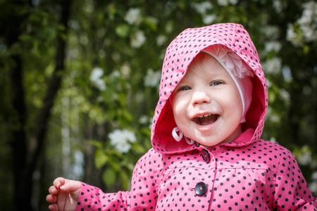 Portrait of a small girl in red dress the park full of apple blossom trees in a spring dayの写真素材