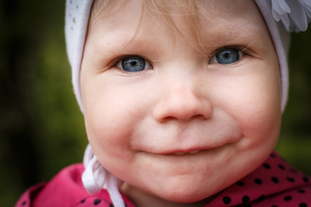 Portrait of a small girl in red dress the park full of apple blossom trees in a spring dayの写真素材