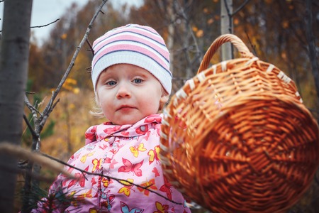 Portrait of a child of a little girl in a warm hat and warm clothes in an autumn dayの写真素材