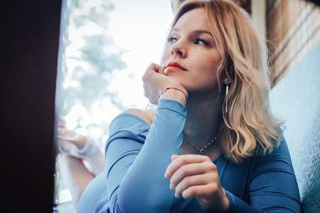 Blond woman in blue dress have rest in cafeの写真素材