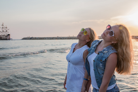 Two blond girls on the beach near sea or ocean. Mother and daughter have fun togetherの写真素材