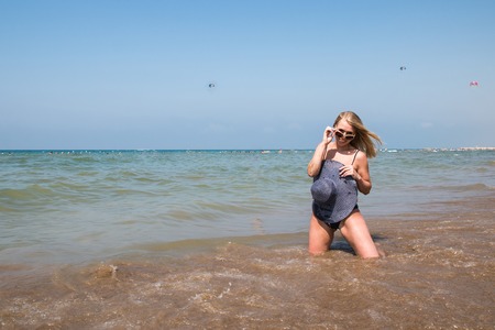 Blond woman on the beach in a water of the sea or ocean