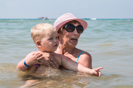 Grandmother and little grandson swim in the sea in summer vacationの写真素材