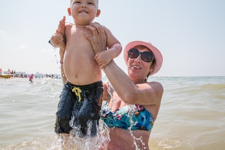 Grandmother and little grandson swim in the sea in summer vacationの写真素材