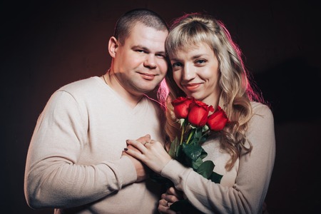 Man and woman in a white dresses lighted colored light in studio and black backgroundの写真素材