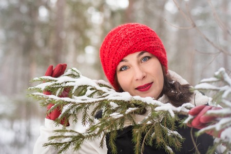 Portrait of girl in a red cap and warm jacket in the forest in a winter day