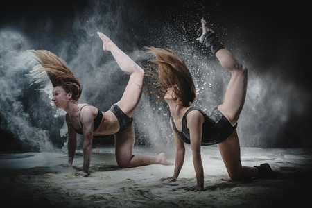 Two girls dance with flour on black backgroundの写真素材