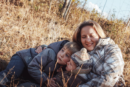 Happy woman and two sons in a field in an autumn dayの写真素材