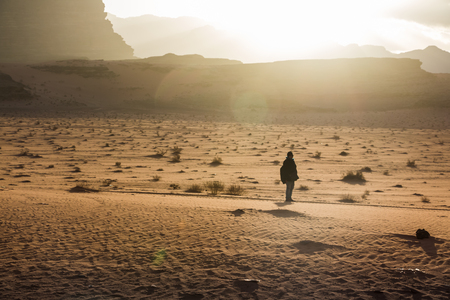 Silhouette of a girl who watches the sunset in Wadi rum desert in Jordanの写真素材