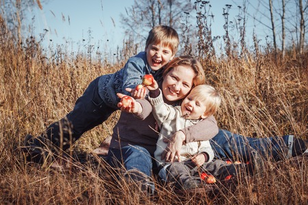 Happy woman and two sons in a field in an autumn day