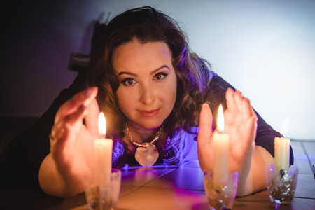 Portrait of fattened girl with black hair and candles in a dark room