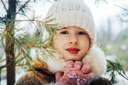 Portrait of a little girl in winter dress in a forest full of snow in a dayの写真素材