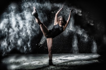 Girl dansing with flour during photoshoot on black backgroundの写真素材