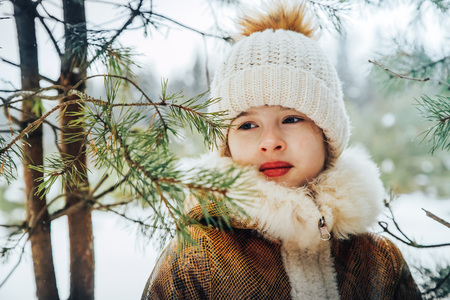 Portrait of a little girl in winter dress in a forest full of snow in a dayの写真素材