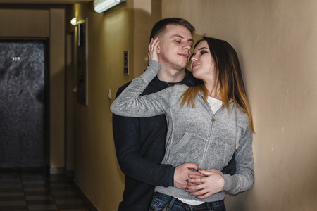 Adult teenagers boyfriend and girlfriend hugging each other in the corridor of an apartment buildingの写真素材