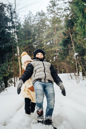 Children have fun in pein forest full of white snow in a winter dayの写真素材