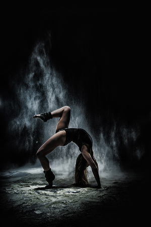 Girl dansing with flour during photoshoot on black backgroundの写真素材