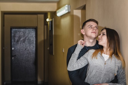 Adult teenagers boyfriend and girlfriend hugging each other in the corridor of an apartment buildingの写真素材