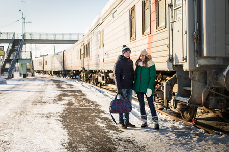 Couple at railway station near train in a winter time and snow aroundの写真素材