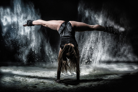 Girl dansing with flour during photoshoot on black background