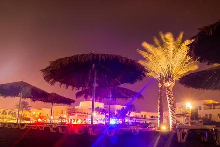 Beautiful evening in a summer night with a beach and umbrellas and colored light bright in Jordanの写真素材