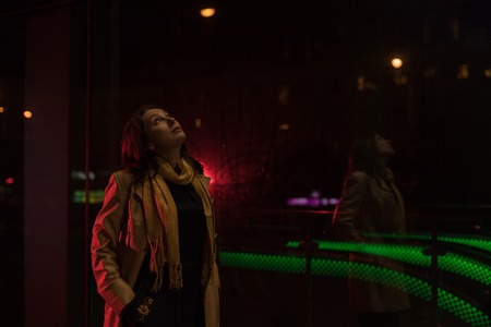 Girl brunette near in the shopwindow on the night city street in a cold time