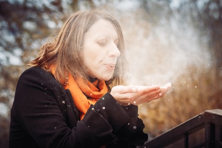 Portrait of a young woman in a black coat and red scarf in the city in a cold dayの写真素材