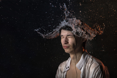 Portrait of attractive young man brunette in wet clothes and splashes of water. Studio photo shoot