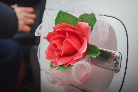 Red flower on the white handle of the carの写真素材