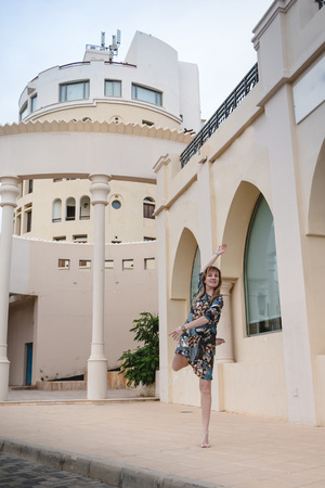 Beautiful slim girl dances near building with column in a summer dayの写真素材