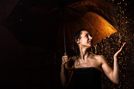 Girl in black dress with umbrella and drops of water during a photoshootの写真素材