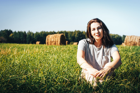Girl in a blue dress in an autumn field with hay stackの写真素材