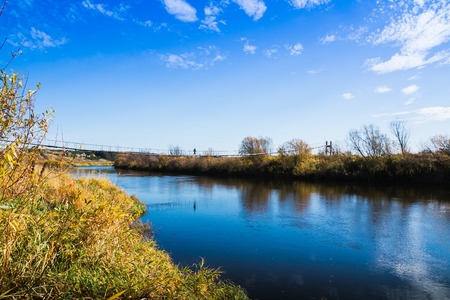 Suspension bridge over the river and the autumn nature aroundの写真素材