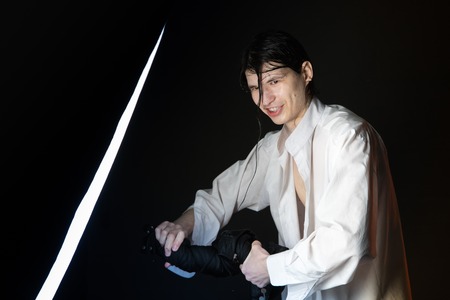 Attractive young man with black hair washes black dress in studio during photo shootの写真素材