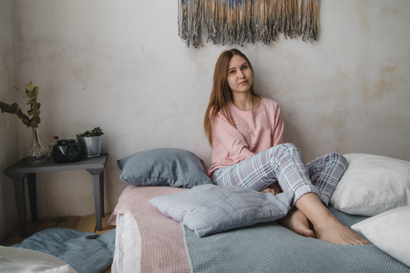 Cute girl in pink pajamas on the bed in sleeping roomの写真素材