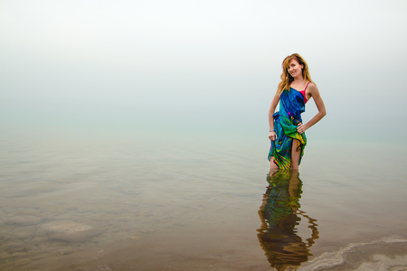 Nice woman stands in water of Dead Sea in Jordan and fog arroundの写真素材