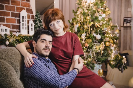 Couple consisting russian wife and turkish husband in the living room decorated for Christmas and New Yearの写真素材