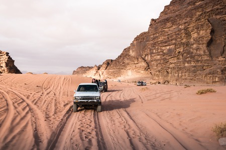 Wadi Rum, Jordan - December, 25, 2017: Bedouin's car jeeps and tourists in it in Wadi Rum desert in...