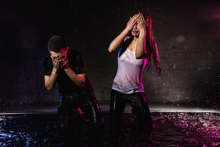 Couple young Teens together in small pool, drops of water and colored light behing themの写真素材