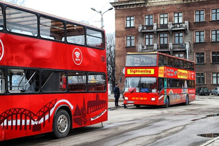 Riga, Latvia - April 01, 2018: Touristic red double-decker hop-on hop-off City Sightseeing tour bus...