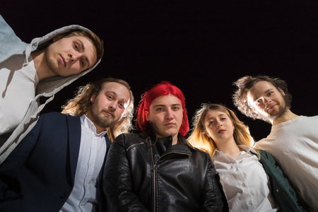 Group of friends having fun together outdoor in a night and light behind themの写真素材